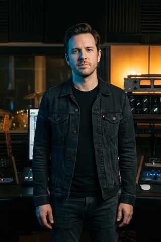 Music producer standing in a dimly lit recording studio